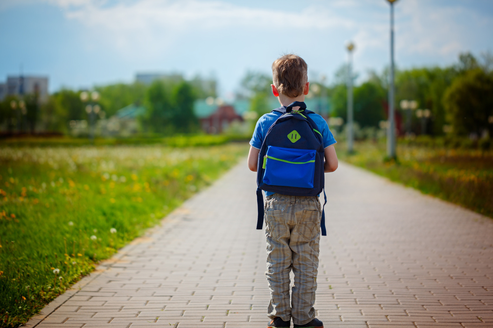 Un enfant anxieux tenant la main de son parent devant l’école, exprimant des signes de nervosité à l’approche de la rentrée scolaire.